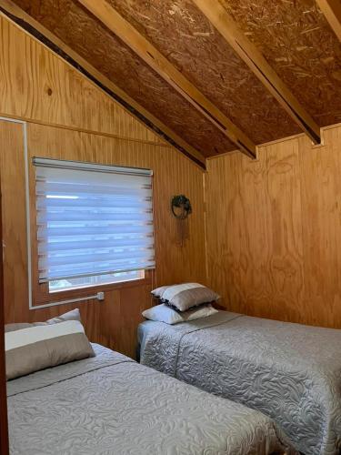 two beds sitting in a room with a window at Cabaña Donde la Bety in Villa Santa Lucía