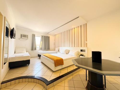 a hotel room with two beds and a table at Império Hotel in Santos