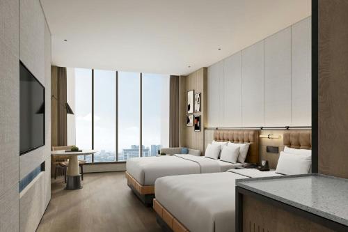 a hotel room with two beds and a television at Four Points by Sheraton Linyi Hedong in Linyi