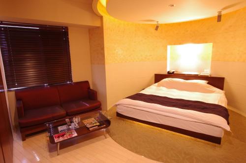 a bedroom with a bed and a couch and a table at Blue Hotel Octa (Adult Only) in Sapporo