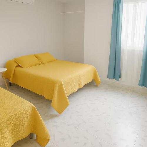 a bedroom with two beds with yellow sheets and a window at Villa Bonita Torre 11 3 in Cozumel