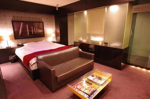 a bedroom with a bed and a couch and a table at Blue Hotel Octa (Adult Only) in Sapporo