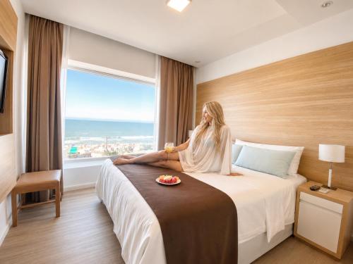 a woman sitting on a bed in a hotel room at Pinamar Beach Resort in Pinamar