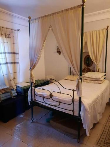 a bedroom with a canopy bed with curtains at La maison des oliviers in Houmt Souk