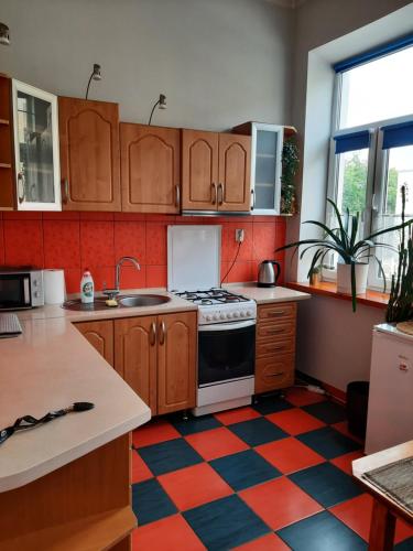 a kitchen with a stove and a checkered floor at Kawalerka w kamienicy in Suwałki