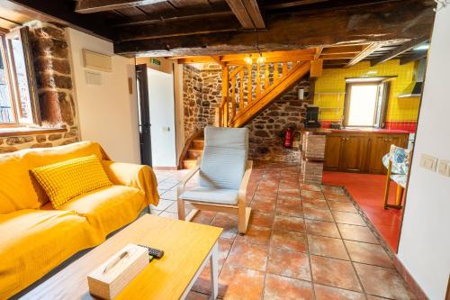 a living room with a yellow couch and a table at El Llagar de Ternín in Villaviciosa