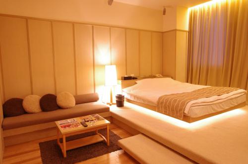 a bedroom with a bed and a couch and a table at Blue Hotel Octa (Adult Only) in Sapporo