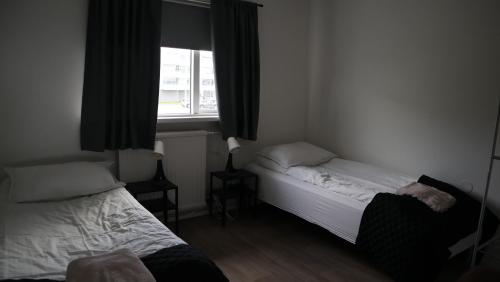 a small bedroom with two beds and a window at Guesthouse Maddy in Húsavík