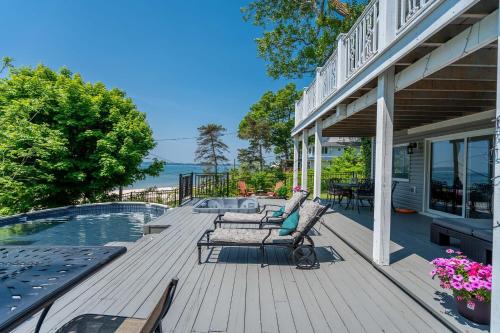 a deck with two chairs and a table next to a pool at Waterfront Cottage w Pool Beach Access in Fort Erie