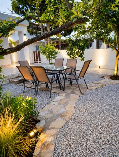 a patio with a table and chairs under a tree at Pipitsa's House-Votsalakia Beach in Votsalákia