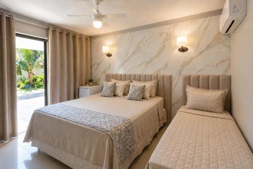a bedroom with two beds and a stone wall at Pousada Recanto do Chef in Búzios