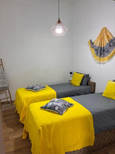 a room with three beds with yellow sheets at Charming House Secret Rose in Flor da Rosa