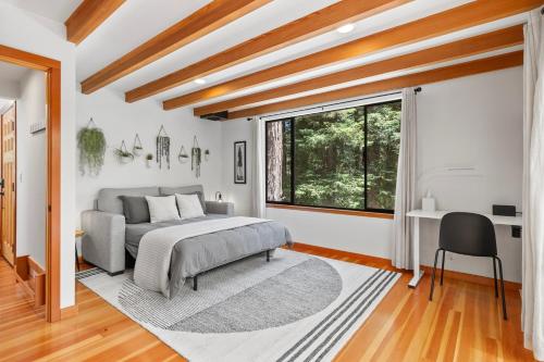 a bedroom with a bed and a desk and a window at Redwood Oasis - Luxe Santa Cruz Cabin w/ Hot Tub in Ben Lomond