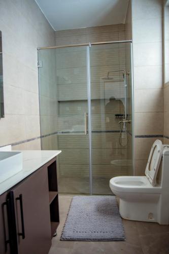 a bathroom with a shower with a toilet and a sink at Kiara Apartments in Kigali