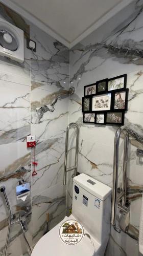 a bathroom with a marble wall with a toilet at شاليهات البدرية لبيوت العطلات in Taif