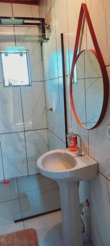 a bathroom with a sink and a mirror and a shower at Chalé Raio de Sol- Colônia Witmarsum in Palmeira