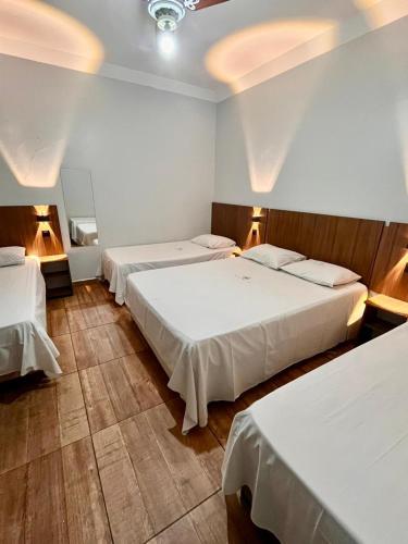 a hotel room with three beds and two lights at New Comercial Palace Hotel in São Paulo