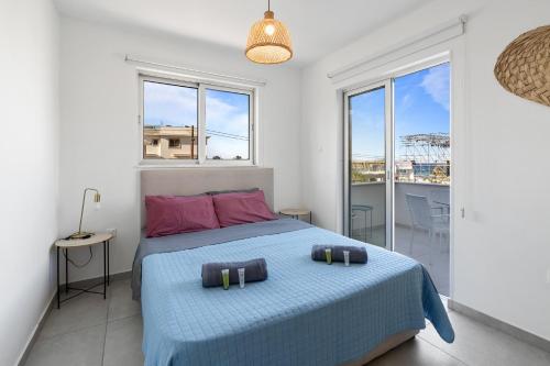 a bedroom with a bed with a blue blanket and windows at WAKE UP BY THE SEA BEACHFRONT FLATS - Protaras in Protaras