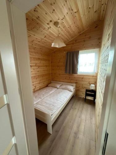 a small bedroom with a bed in a wooden room at Baltic Holidays in Gąski