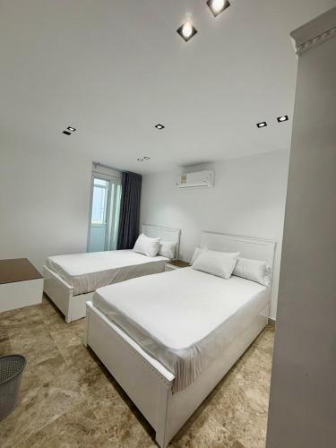 two beds in a room with white walls at Retaj Waterfront Penthouse in Port Said