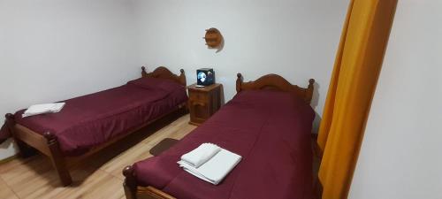 two beds in a room with purple sheets at Complejo Cerro Morado in Villa Unión