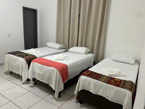 three beds in a room with white walls at Casa no centro in Primavera do Leste