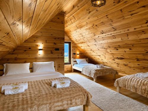 two beds in a room with wooden walls at Grahovo Mountain Chalet in Grahovo