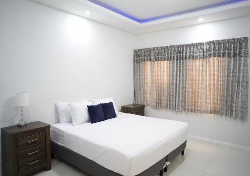 a white bedroom with a bed and a window at Onyx Villa in Ocho Rios