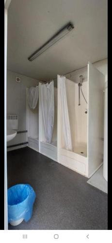 a bathroom with a shower and a blue ottoman at Domek GLAMPING na Polu namiotowym RADOŚĆ in Okuninka