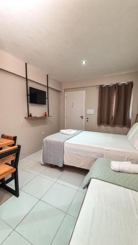 a hotel room with two beds and a tv at Pousada BOB Suítes in Porto De Galinhas