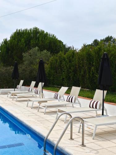 a row of lounge chairs next to a swimming pool at Montes da Salvada in Melides