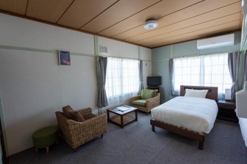 a bedroom with a bed and a couch and chairs at 暮泊くらはく 1日 1組様限定 5名様まで宿泊可能 in Mikasa