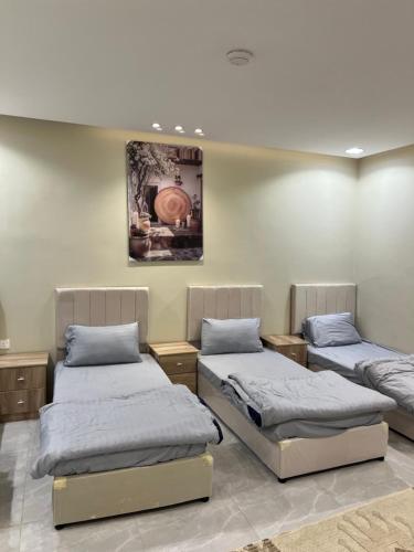 a room with three beds and a painting on the wall at فيلا ايمان مسبح وحوش وجلسات خارجيه مع ملعب كرة قدم in Taif