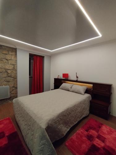 a bedroom with a large bed and a red rug at Casa da Aldeia in Santa Cruz do Douro