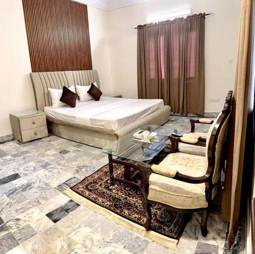 a bedroom with a bed and a table and chairs at Hotel Moon Light view in Lahore