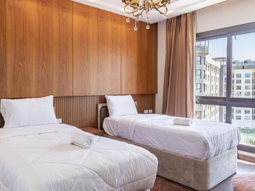 two beds in a hotel room with a window at Porto New Cairo - بورتو نيو كايرو in Cairo