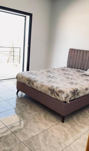 a bed in a room next to a window at La vague in Île Pilau