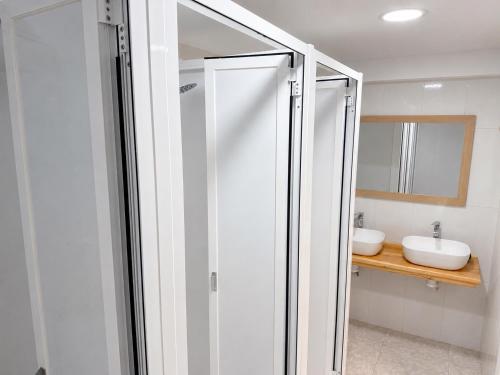 a bathroom with a glass shower with a sink at CH Arzúa Pilgrim Hostel in Arzúa