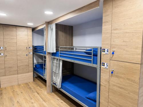 a bunk room with blue bunk beds and wooden cabinets at CH Arzúa Pilgrim Hostel in Arzúa