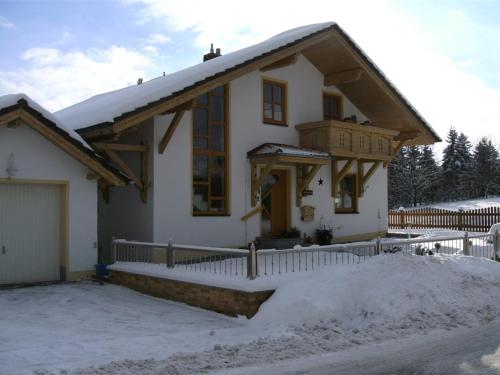 una pequeña casa blanca con nieve delante en Ferienwohnungen Malz, en Blaibach
