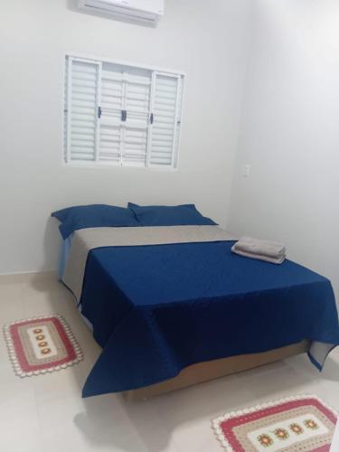 a blue bed in a white room with a window at Pousada Do Goiano in Manhã