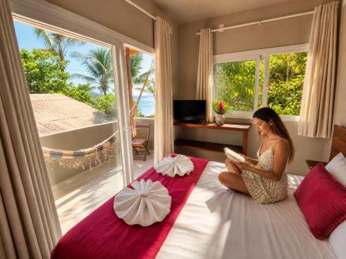 a woman sitting on a bed reading a book at Monkey beach agroturismo in Gamboa