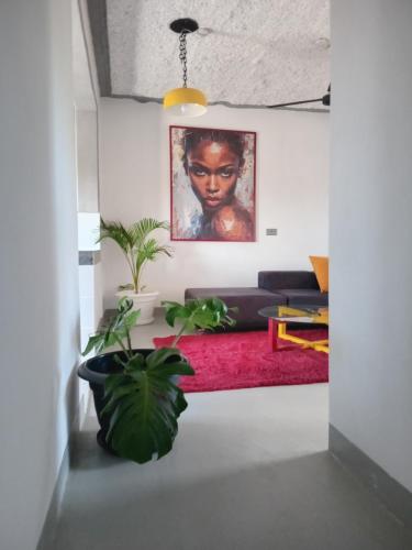 a living room with plants and a painting on the wall at TN Apartments deviat in Diani Beach