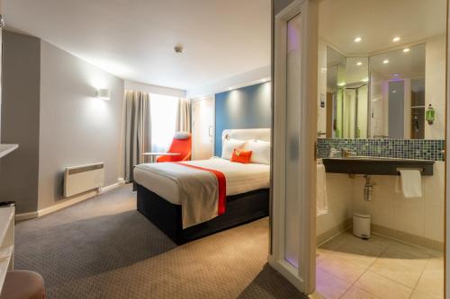 a hotel room with a bed and a bathroom at Holiday Inn Express Glasgow City Theatreland by IHG in Glasgow