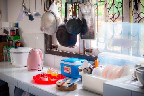 a kitchen counter with pots and pans hanging above it at Honey You HOSTEL in Ban Khlong Mat