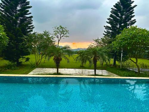a blue swimming pool with trees in the background at Solmist Villa in Hòa Bình