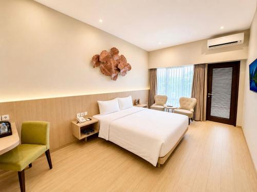 a hotel room with a white bed and a chair at Grand Whiz Hotel Trawas Mojokerto in Trawas