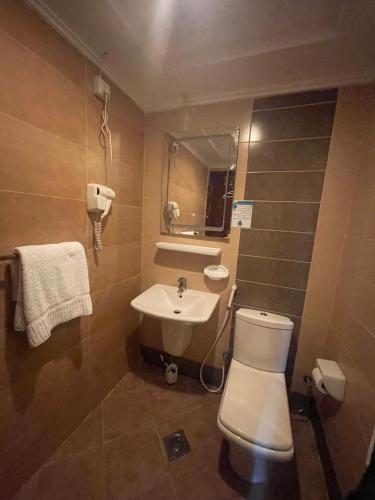 a bathroom with a white toilet and a sink at فندق ريماس العنود in Mecca