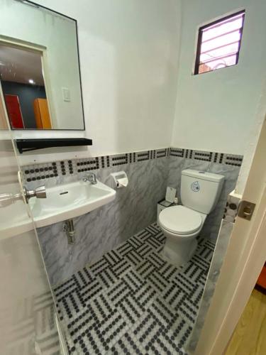 a bathroom with a toilet and a sink and a mirror at Angkel's Place in Bangued
