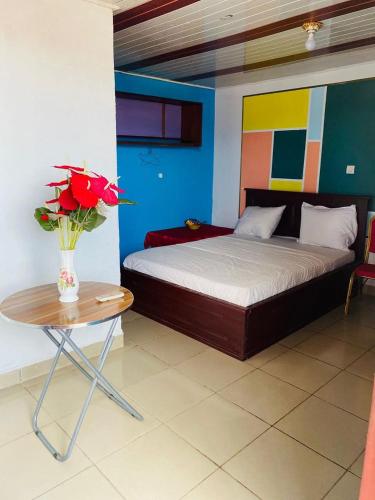 a bedroom with a bed and a table with a vase of roses at Hôtels Bali in Yaoundé